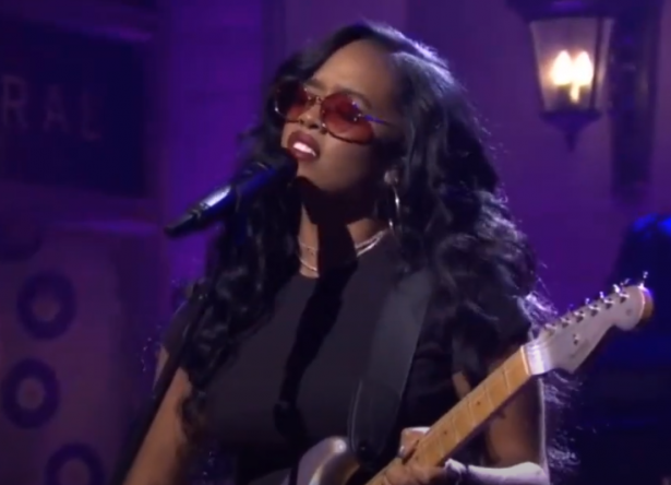 H.E.R tocando guitarra e cantando no microfone (Reprodução)